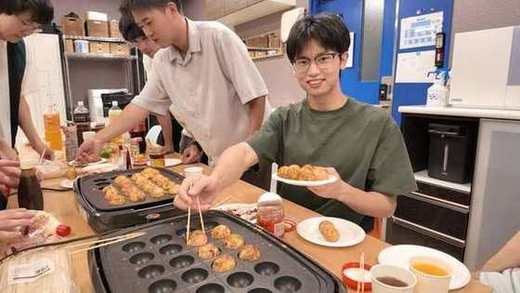 焼き上がったたこ焼きを手にするメンバー