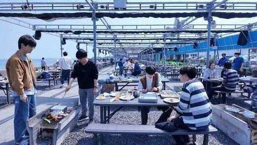 海辺のBBQ会場で食事をするメンバー